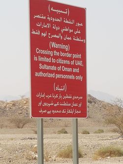 Road sign at border point Hatta/المدام road يمر خلال محضة