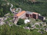 A complex of buildings partially in ruins in a mountain landscape.