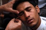 كما يتبع في ثاني أيام شهر رمضان، أحد المعالجين يضع الكحل لشاب يمني، 23 أغسطس، 2009.