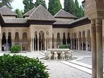 A courtyard with a gallery and a basin supported by lion sculptures.
