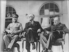 Three men, Stalin, Roosevelt and Churchill, sitting together elbow to elbow